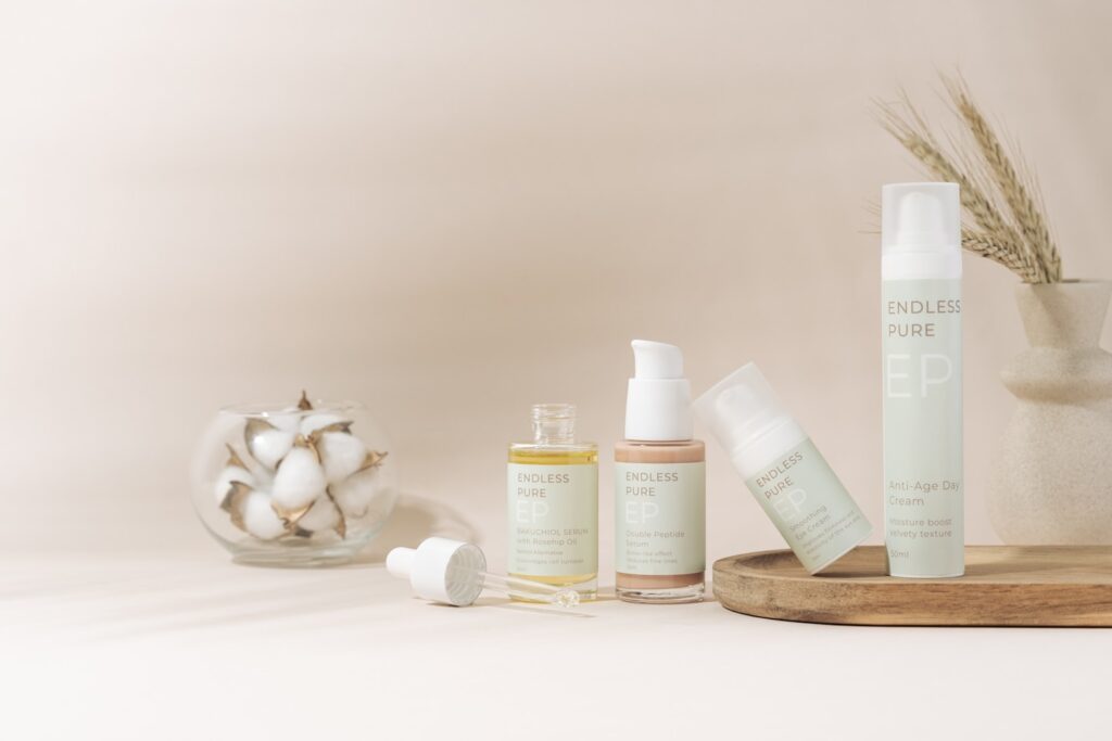 A beautifully arranged display of elegant skincare products on a marble tray against a soft, beige backdrop. The collection includes various bottles and jars, showcasing a range of serums, creams, and SPF protection. The minimalist design and soft pastel colors create a clean, luxurious aesthetic. A delicate floral arrangement in a textured vase adds a natural touch to the composition, enhancing the serene and sophisticated vibe.