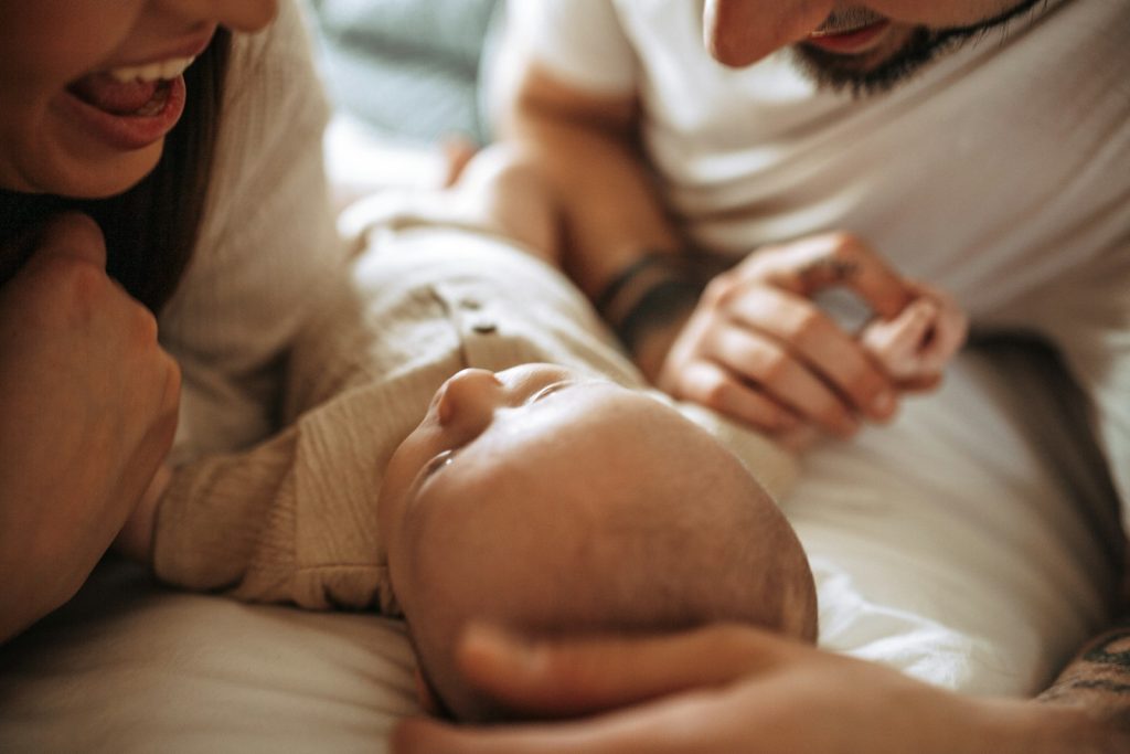 Parents souriants penchés sur leur nouveau-né allongé sur le lit, de retour à la maison